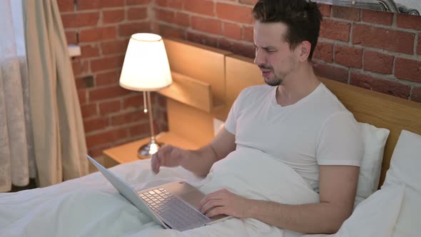 Focused Young Man Get Shock on Laptop in Bed