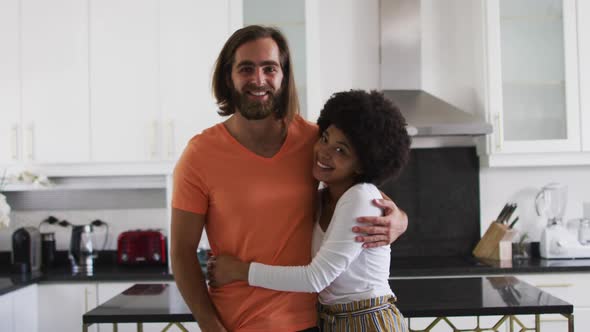 Portrait of mixed race couple smiling and hugging in the kitchen at home