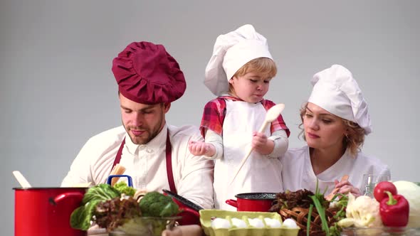 Young Family Cooking in Chef Hat, Couple and Child Have Fun Cooking Baking at Home Together, Happy