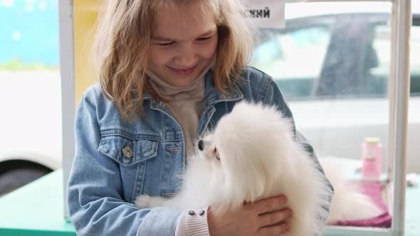 a Small and Happy Girl with a White and Fluffy Spitz Puppy