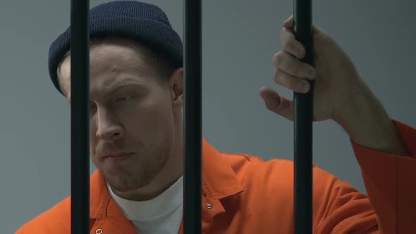 Caucasian Criminal Looking at Camera Through Prison Bars, Waiting for Judgment