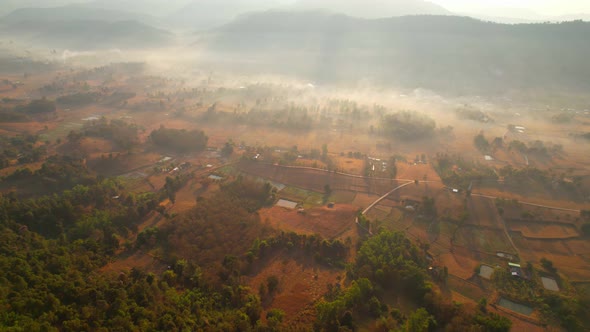 Aerial view over villages and barren fields in countryside during sunrise