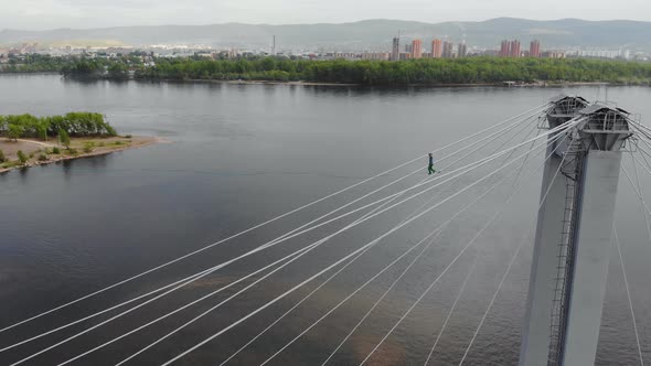 A Man Walks on a Rope Stretched Between the Supports of the Bridge at High Altitude alt