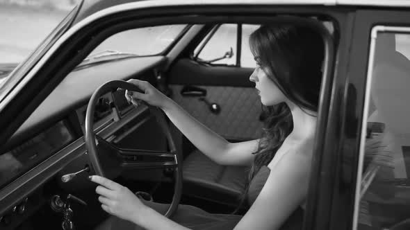 a Woman Sits Behind the Wheel of a Vehicle is Similar to a Retro Movie Character