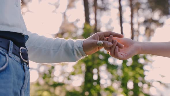 Close up, romantic couple holding eachothers hands outdoors in green forest