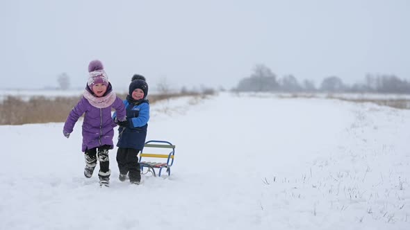 Happy children play with sledges in a beautiful winter park.