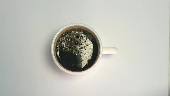 Preparing a cup of black instant coffee. Hot water is poured into a white mug with black instant cof