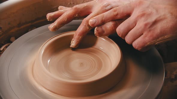 Pottery - Man with Finger Is Making the Bottom for a Clay Bowl on the Potter's Wheel