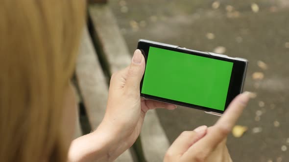 Outdoor blond female holding green screen display cellular phone  4K 2160p 30fps UHD footage - Green