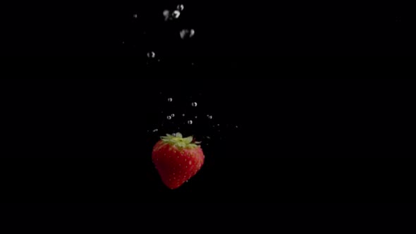 Strawberry Falling into Water Super Slowmotion, Black Background, lots of Air Bubbles, 4k240fps