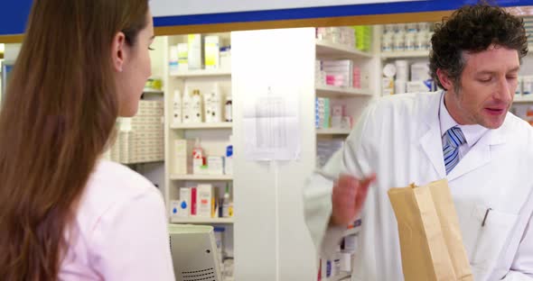 Pharmacist giving medicine package to customer