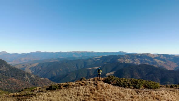 Aerial Man Hiker Standing on Ridge Overlooking Mountain Valley 