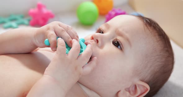 Infant Childhood Concept  Closeup of Smiling Happy Baby Plays with a Teether