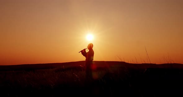 Sunset Silhouette of a Man Playing the Pipe