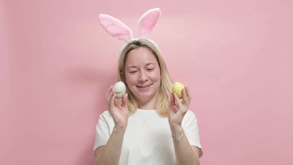 Beautiful Girl in Easter Bunny Ears Holding Painted Easter Eggs on Pink