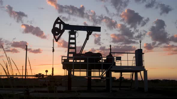 Oil Rig Stands in a Field at Sunset and Extracts Minerals