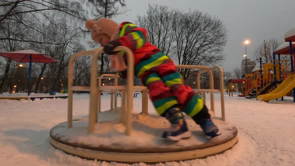 Little Child Playing in the Yard in Winter Evening