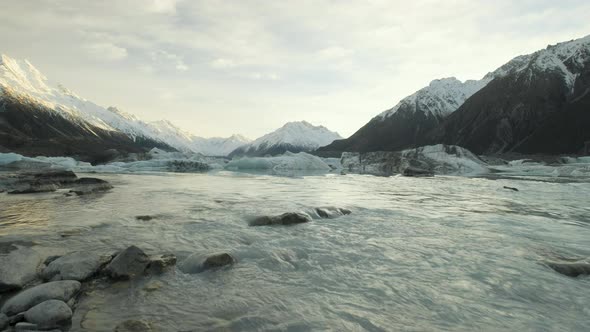 Low angle reveal shot of Tasman Lake in New Zealand at sunrise on a cold winters morning.