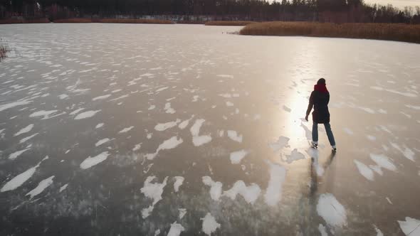 Aerial View. A Young Woman Is Skating on a Frozen Lake.