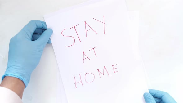 Doctor Hand in Latex Gloves Holding a Paper Written Stay at Home