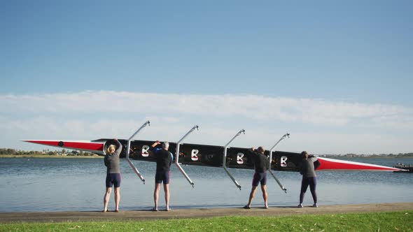 Four senior caucasian men and women carrying a rowing boat together