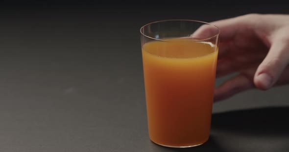 Slow Motion Man Hand Take Pumpkin Juice in Tumbler Glass on Black Background