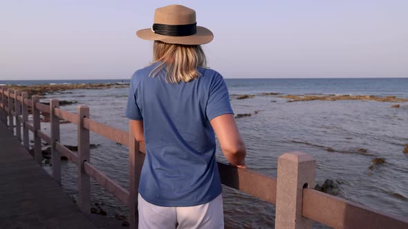 Middle aged woman wearing t-shirt and standing on by the sea