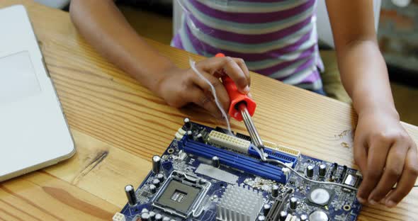 Girl soldering a circuit board at desk 