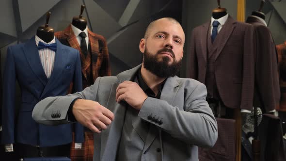 Successful Businessman with a Beard Puts on a Jacket in a Tailor Shop. Satisfied Customer on the