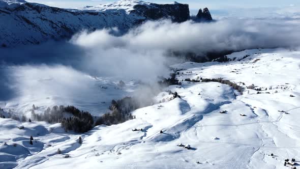 Flying over the winter scenery in the Italian Dolomites, while clouds are moving in front of the pea