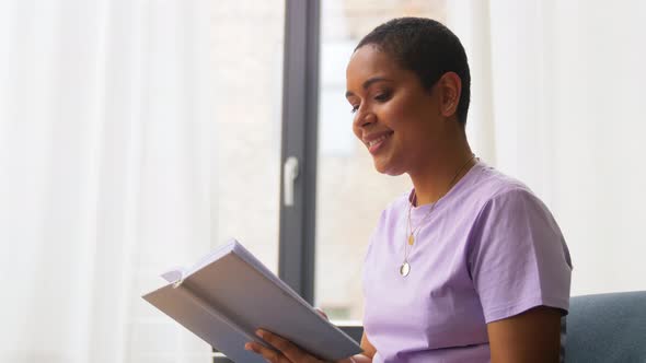 Happy African American Woman Reading Book at Home