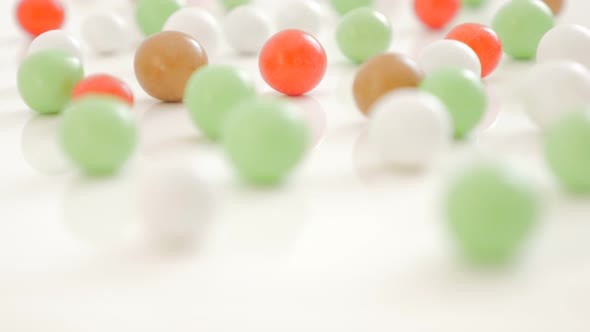 Colorful bonbons on white reflective background randomly positioned 4K 2160p 30fps UltraHD video - L