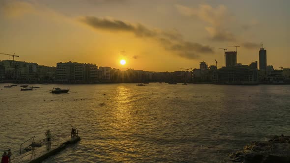 Golden hour at Sliema with people enjoying a swim, Malta, time lapse