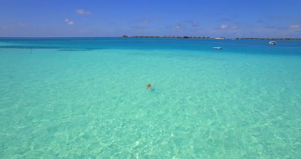 Aerial drone view of a woman floating and swimming on a tropical island.