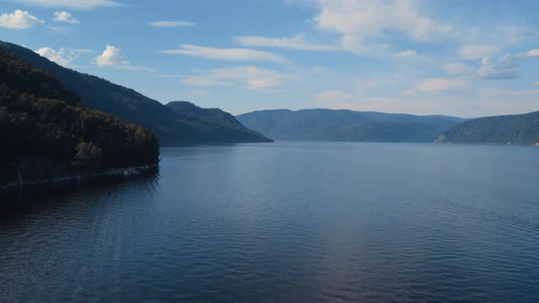 Coastline of lake Teletskoye with forest and blue clear sky in Altai