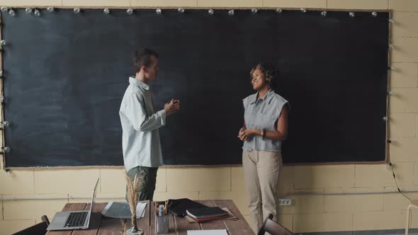 Man and Woman Chatting by Blackboard