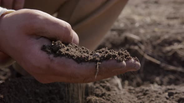 Man's hand sifting through soil, preparing for planting, agriculture, close up