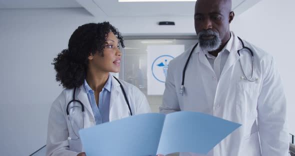 African american male and female senior doctors discussing over medical reports at hospital