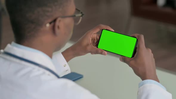 Young African Doctor Looking at Smartphone with Chroma Screen