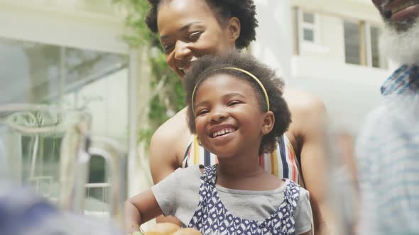 Happy african american family talking and having breakfast in garden