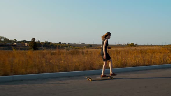 Woman in a Black Dress Is Longboarding on a Country Road, Sports, 