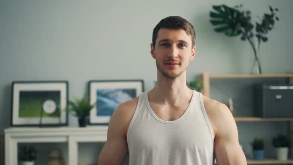 Slow Motion Portrait of Handsome Young Man Looking at Camera and Smiling at Home