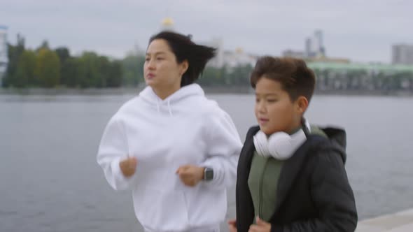 Asian Woman Jogging with Young Son