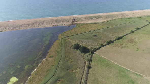 Aerial tracking forward angled down on the fleet lagoon and the western edge with mud tracks leading