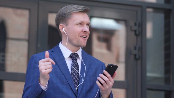 Happy Dancing Businessman Listening Music on Smartphone