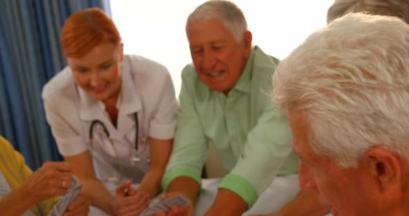 Doctor watching senior people playing cards