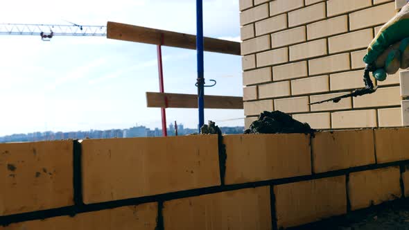 One Person Lays Bricks While Building a House. Bricklayer Doing Brickwork at a Construction Site.