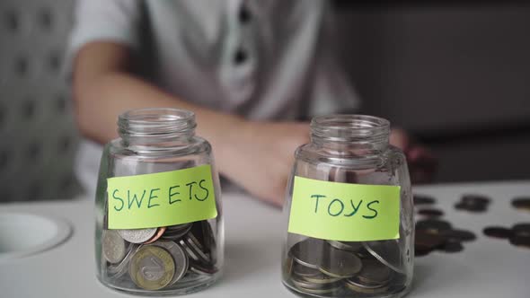 little caucasian boy putting coin into glass bottle. Kid saving money for sweets and toys