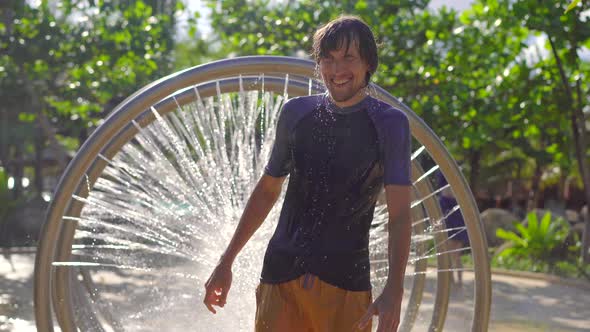 A Young Man Runs Through a Circular Massage Shower in Aqua Park