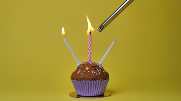 Birthday Cupcake with Candles and Birthday Decorations on Yellow Background